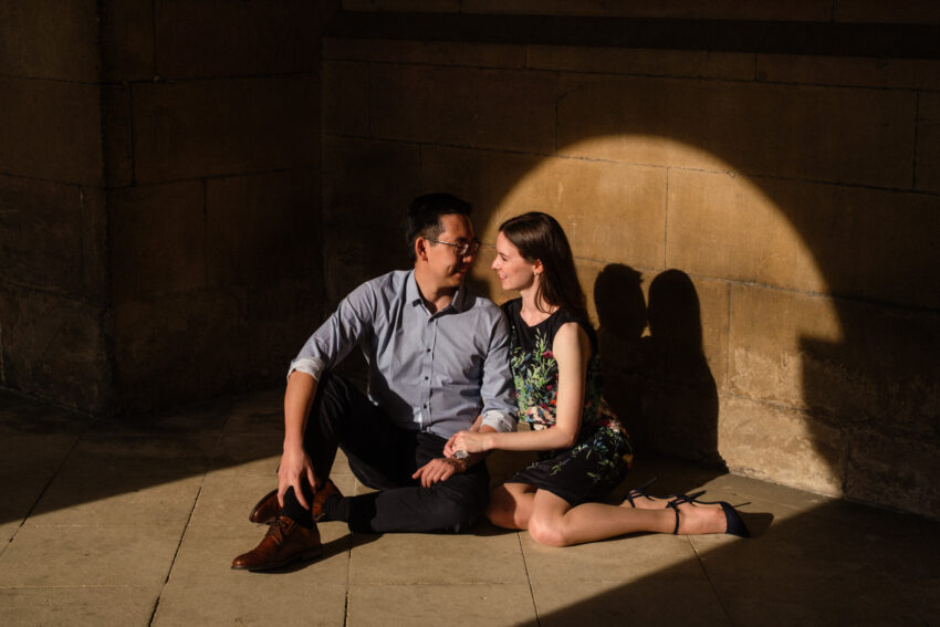 Portrait at golden hour of a couple. Soft light shines through cloisters in a Cambridge college.