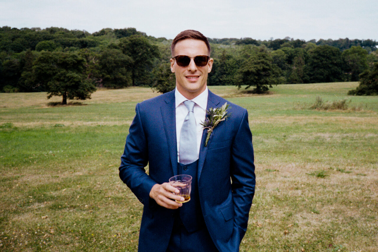 A groom holding a glass of whiskey - photographed with analogue film.