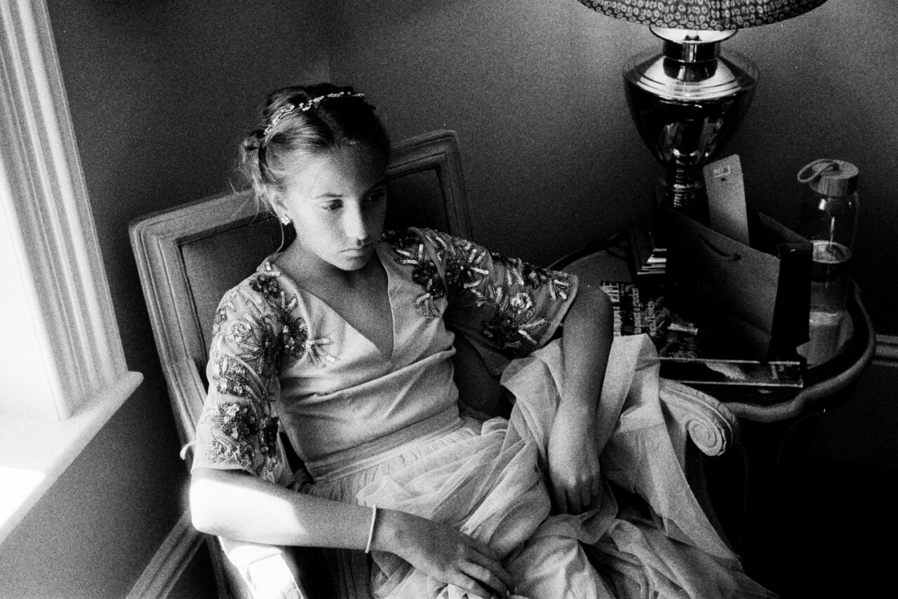 Wedding guest photographed with grainy black and white film - she is sitting on a chair.