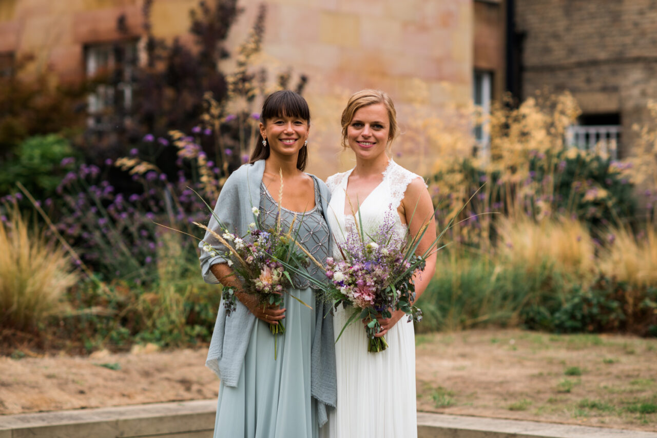 A bride and her bridesmaid in the courtyard at Downing.