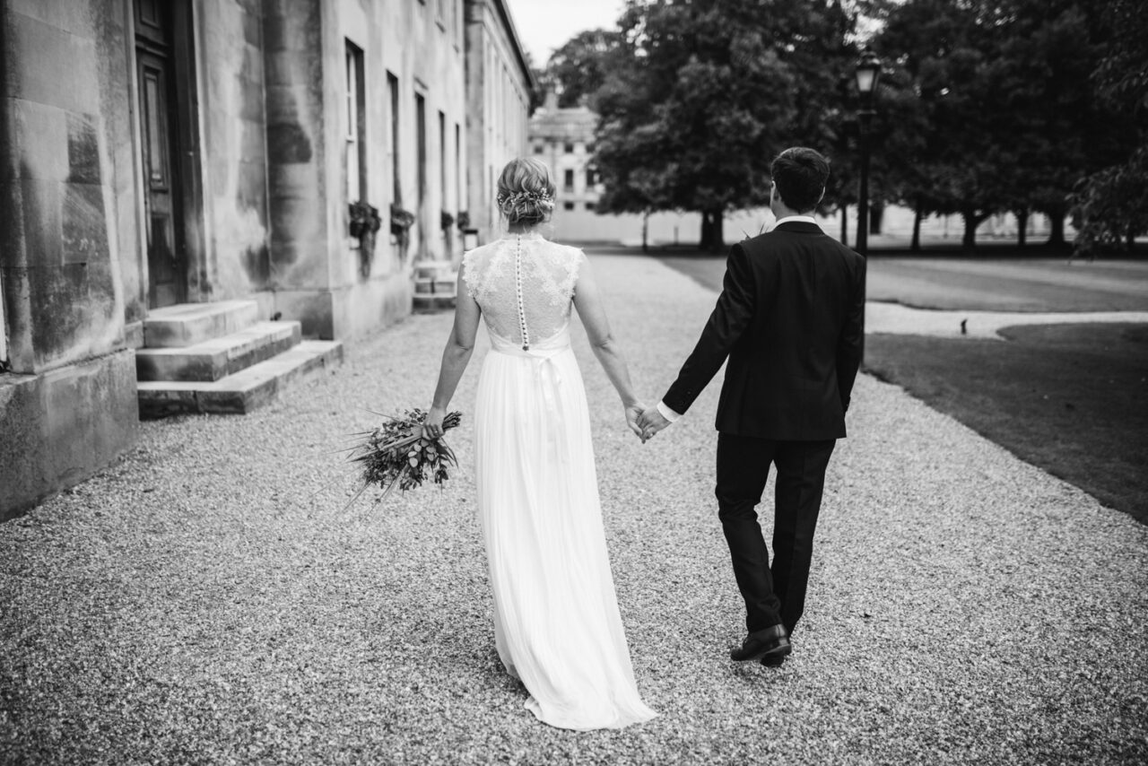 A bride and groom walk in the grounds of Downing College.