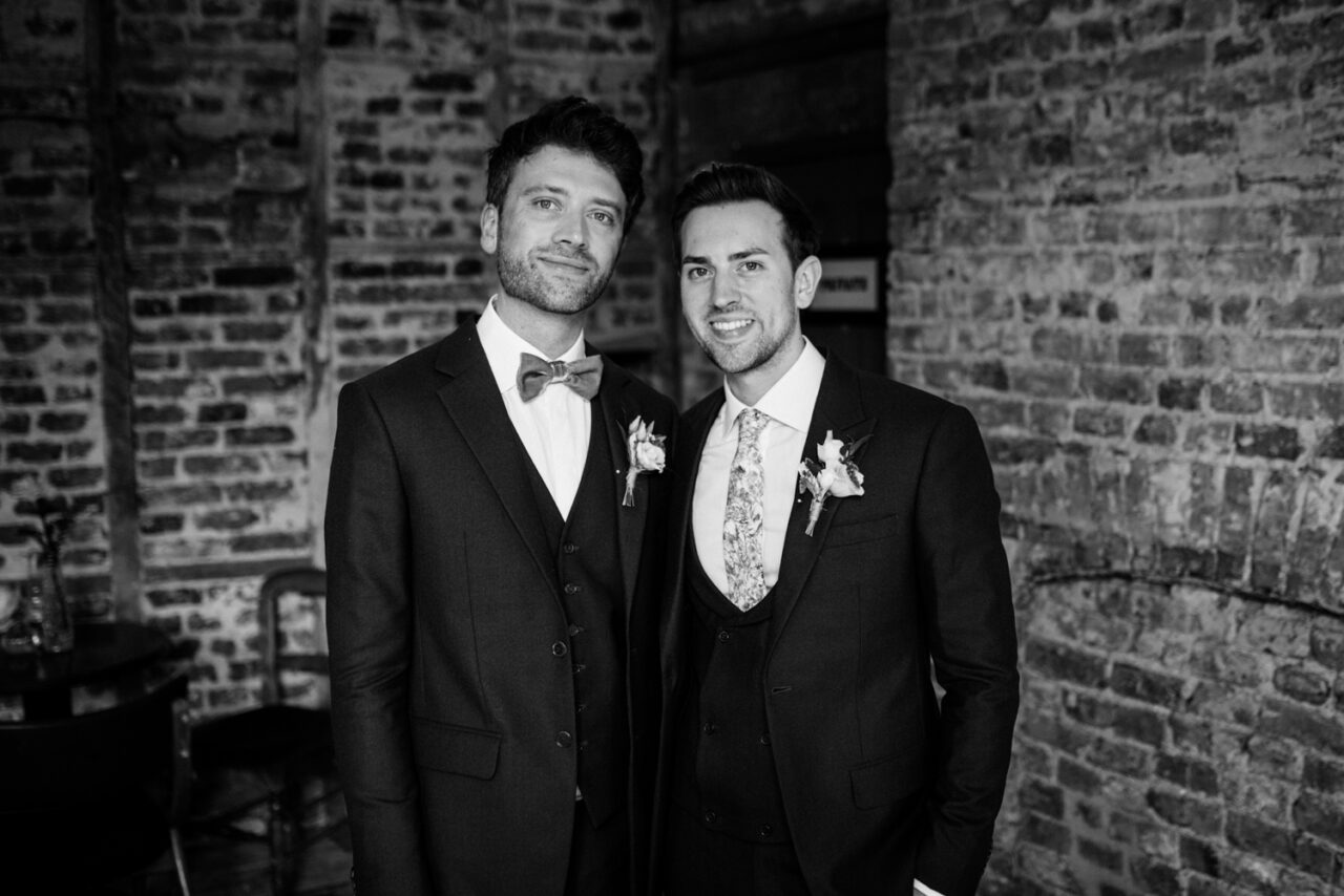 Two grooms standing together at their London wedding.