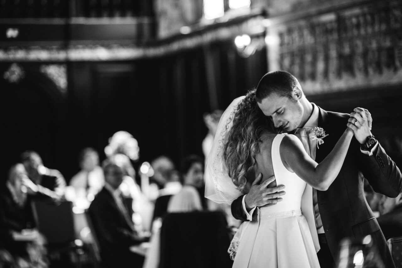 A bride and groom dancing together in the Hall of Queens' College in Cambridge.