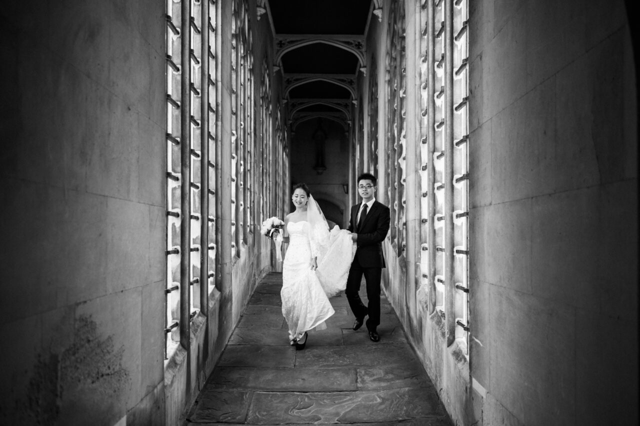 A newly married couple walk across the Bridge Of Sighs in Cambridge.