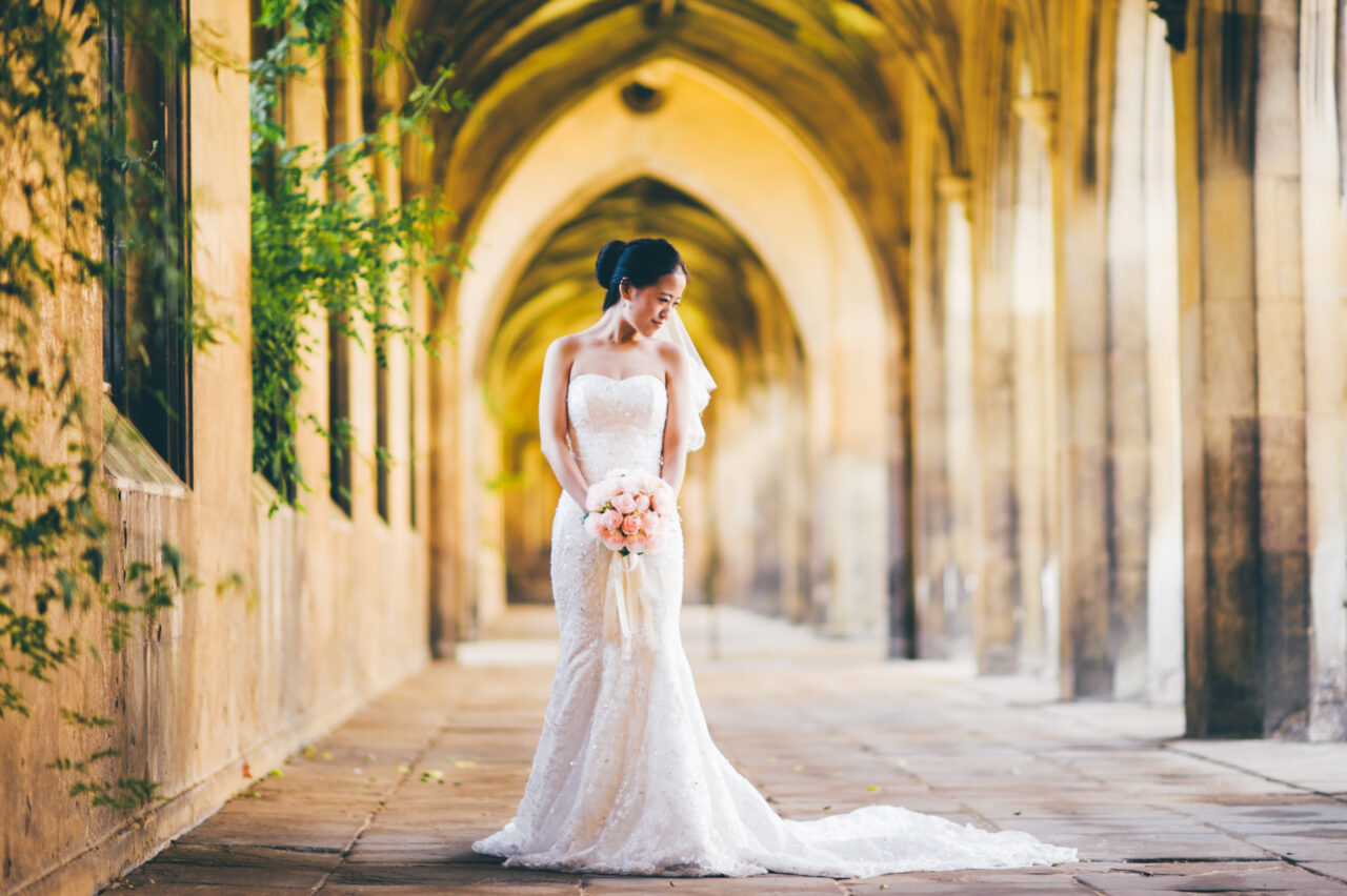 A bride holding flowers in the Cloisters of the College of St John the Evangelist in the University of Cambridge.