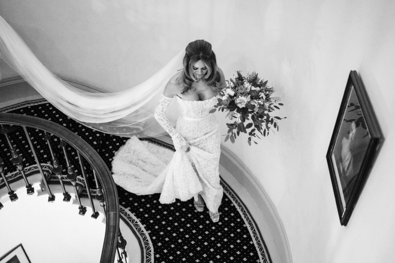 Wynyard Hall Wedding Photographer - A bride walks down the stairs of Wynyard with her veil trailing behind her.