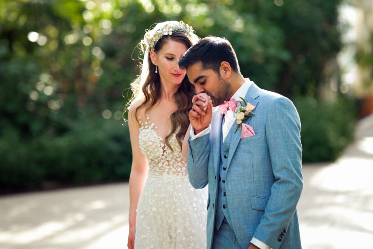 A wedding at Kew Gardens in Richmond, London - A groom kisses the bride's hand.