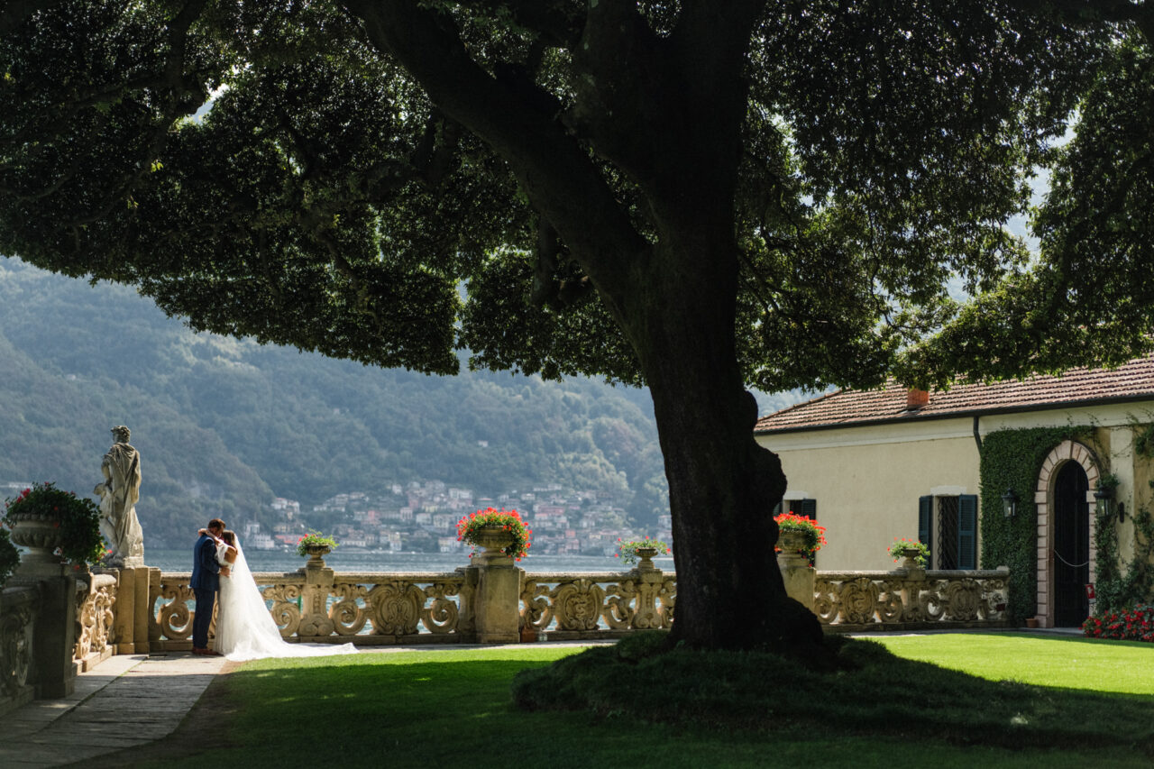 A bride and groom embracing next to the famous tree at Villa del Balbianello during their elopement.