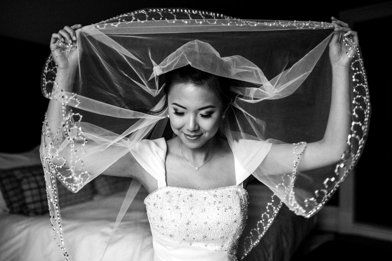 Black and white wedding photo of a bride holding her veil.