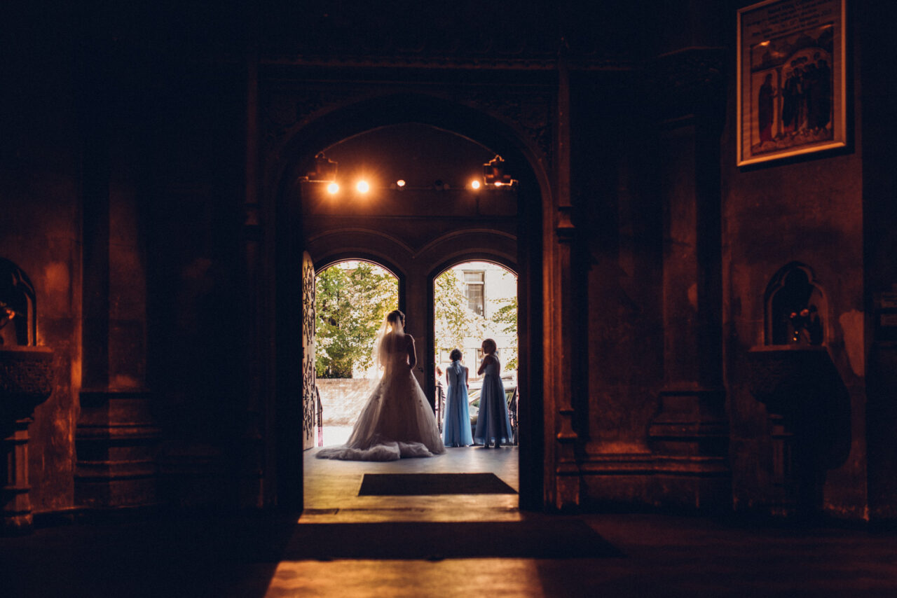 Reportage style picture of a bride and bridesmaids waiting in a church in Cambridge.