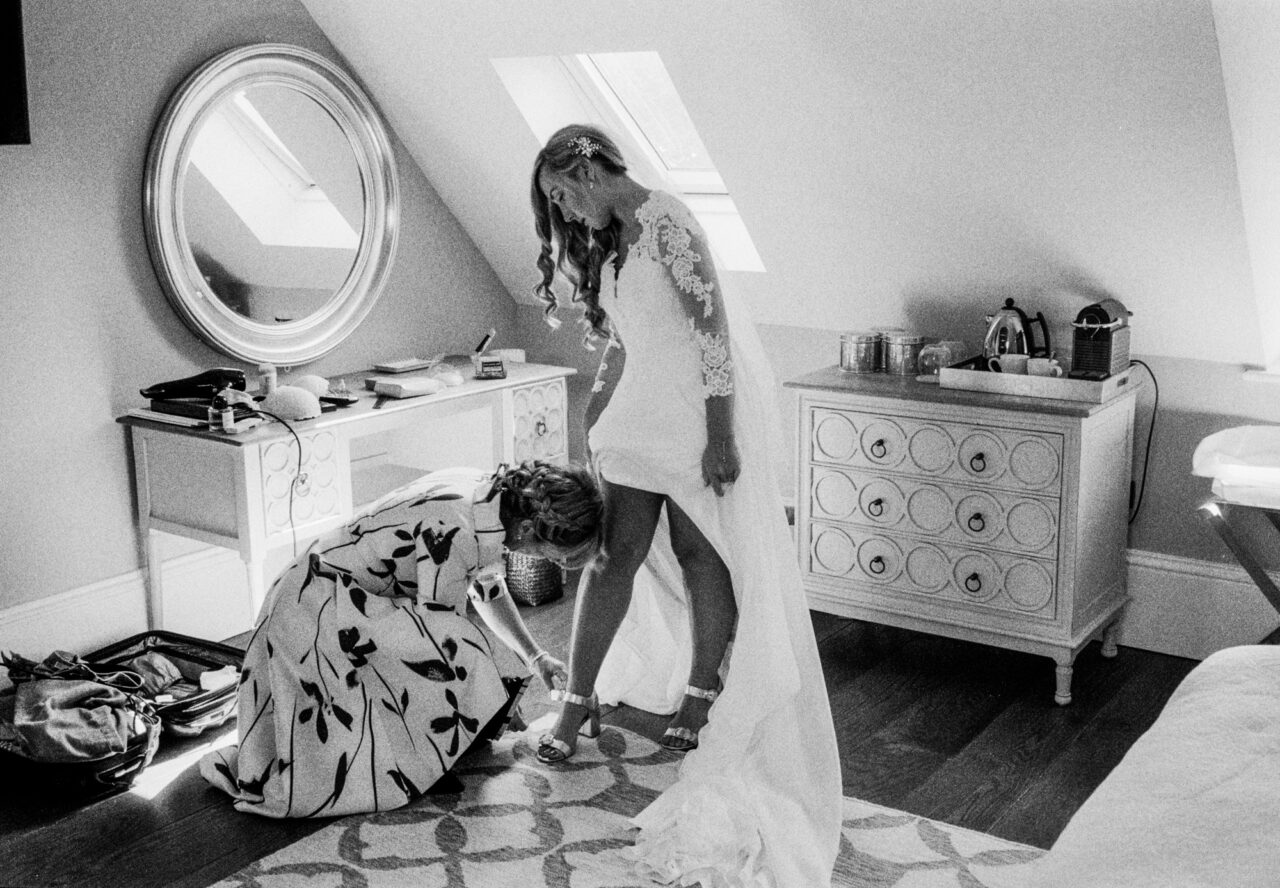 Documentary wedding photo of a bride getting ready - her mother is helping her into her shoes.