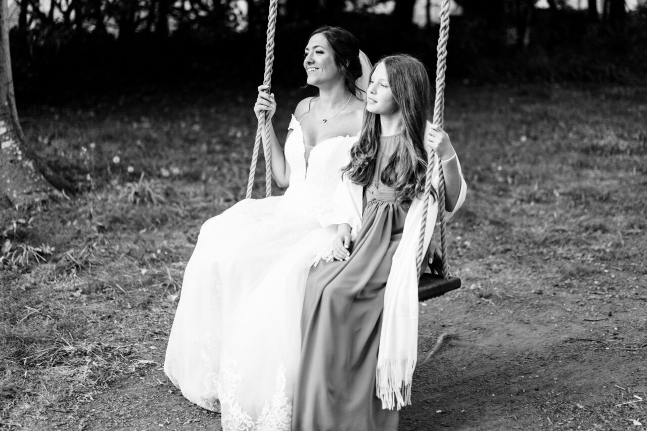 A bride and her flower girl play on the swing at Hockwold Hall.