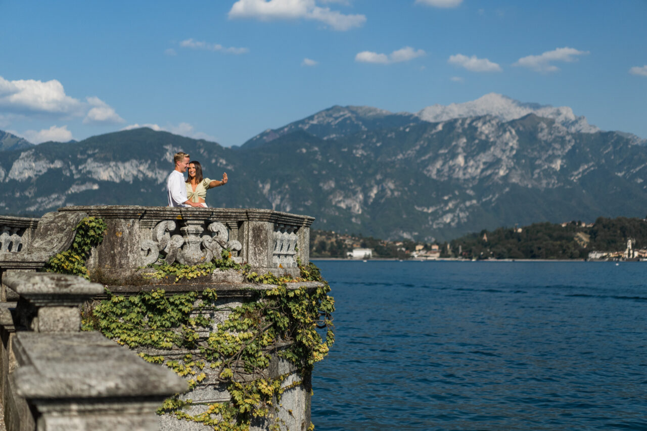 A woman looks at her new engagement ring with Lake Como and mountains in the background.