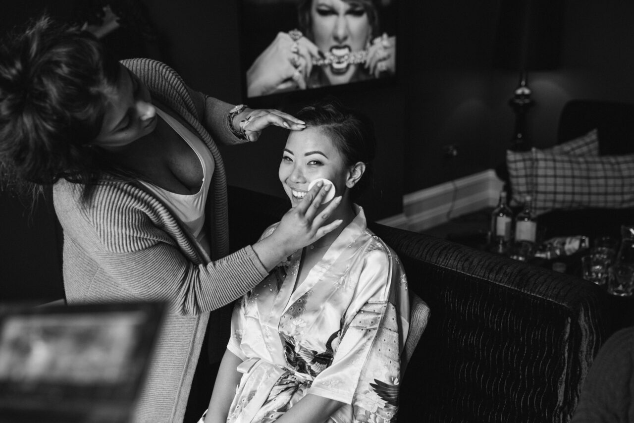 A bride has makeup applied at Swynford Manor. Taylor Swift is on the TV behind her.