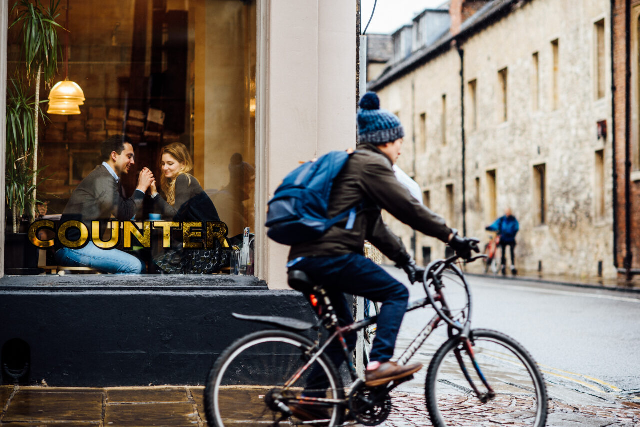 A couple hold hands in the window of Fitzbillies on Trumpington Street in Cambridge.