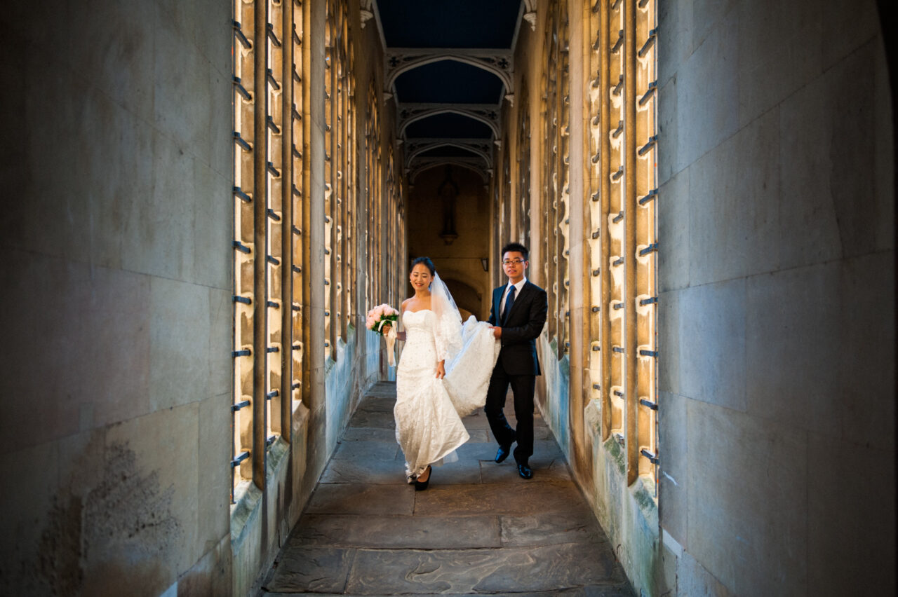 A bride and groom walk over The Bridge Of Sighs at St John's College in Cambridge.