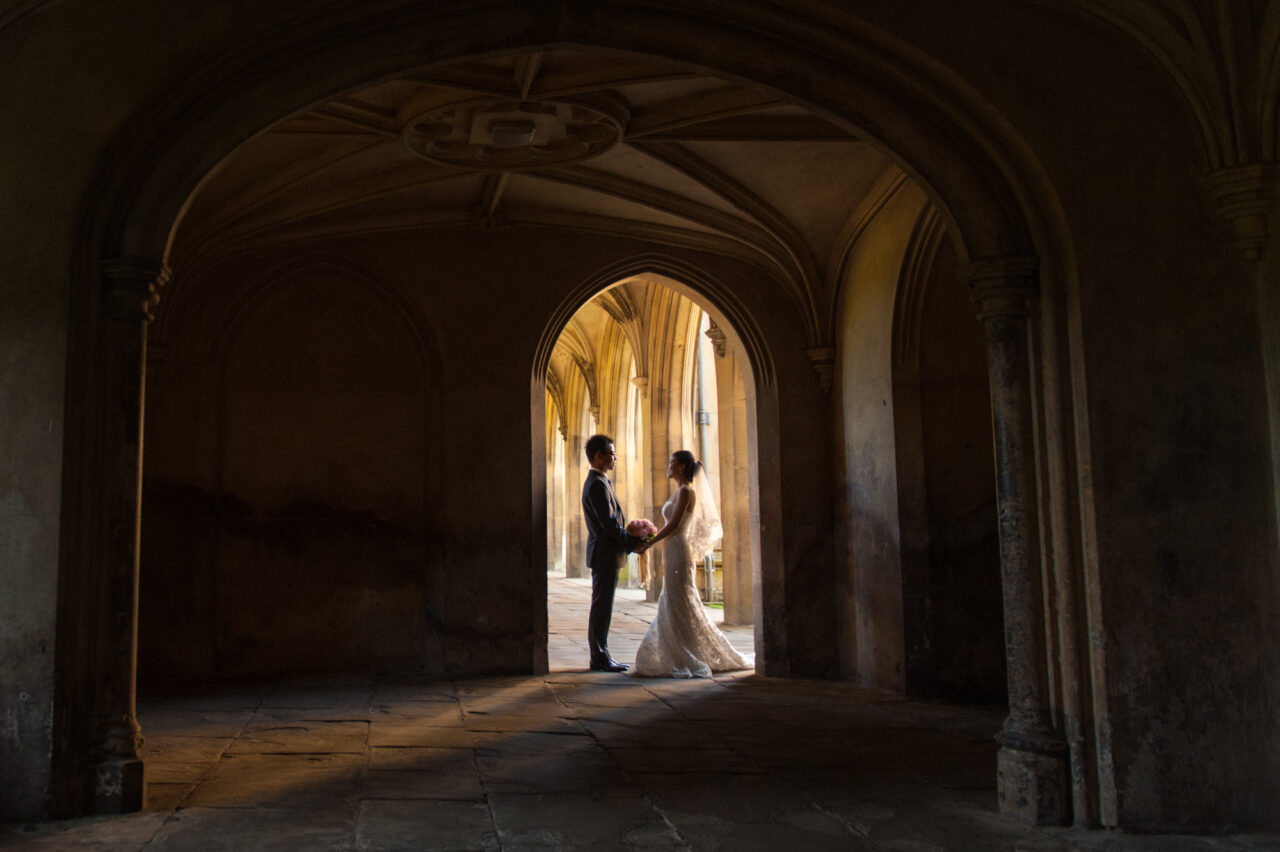 A bride and groom pose in the cloisters at St John's College in Cambridge.