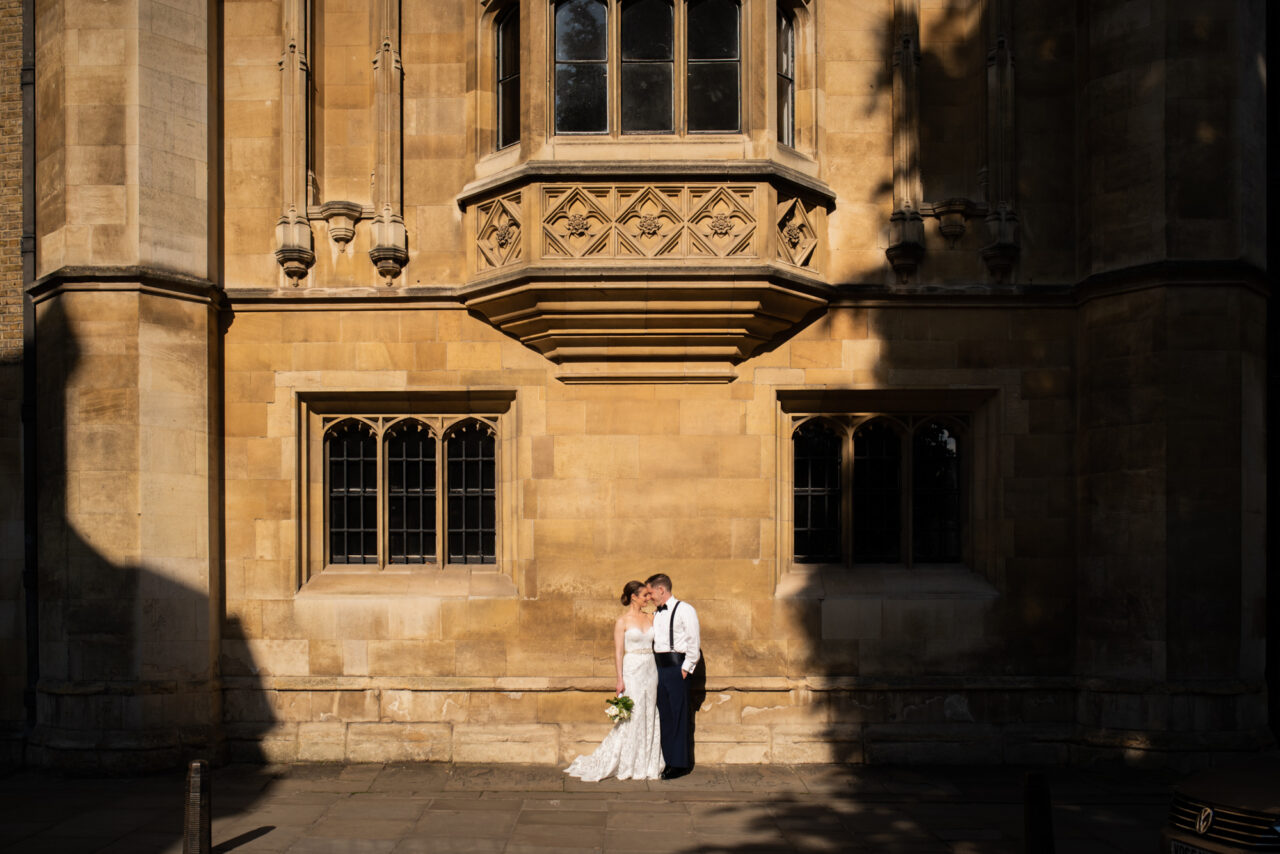 A couple pose on a street in Cambridge, surrounded by shadows.