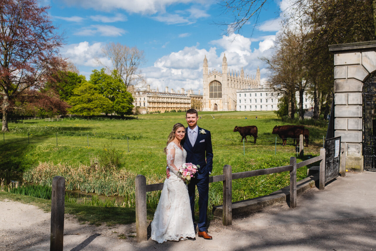 Cambridge pre-wedding photography at The Backs. The bride and groom stand with King's College and some cows in the background.