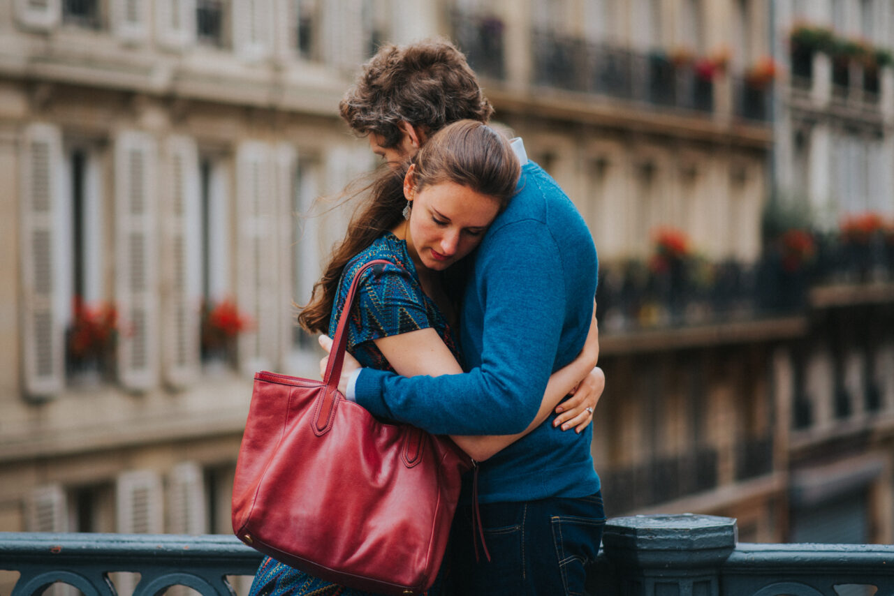 Man and woman embrace on a bridge for a pre-wedding photoshoot.