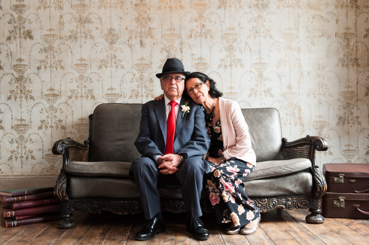 A mother and father of the groom on a sofa in beautiful window light.