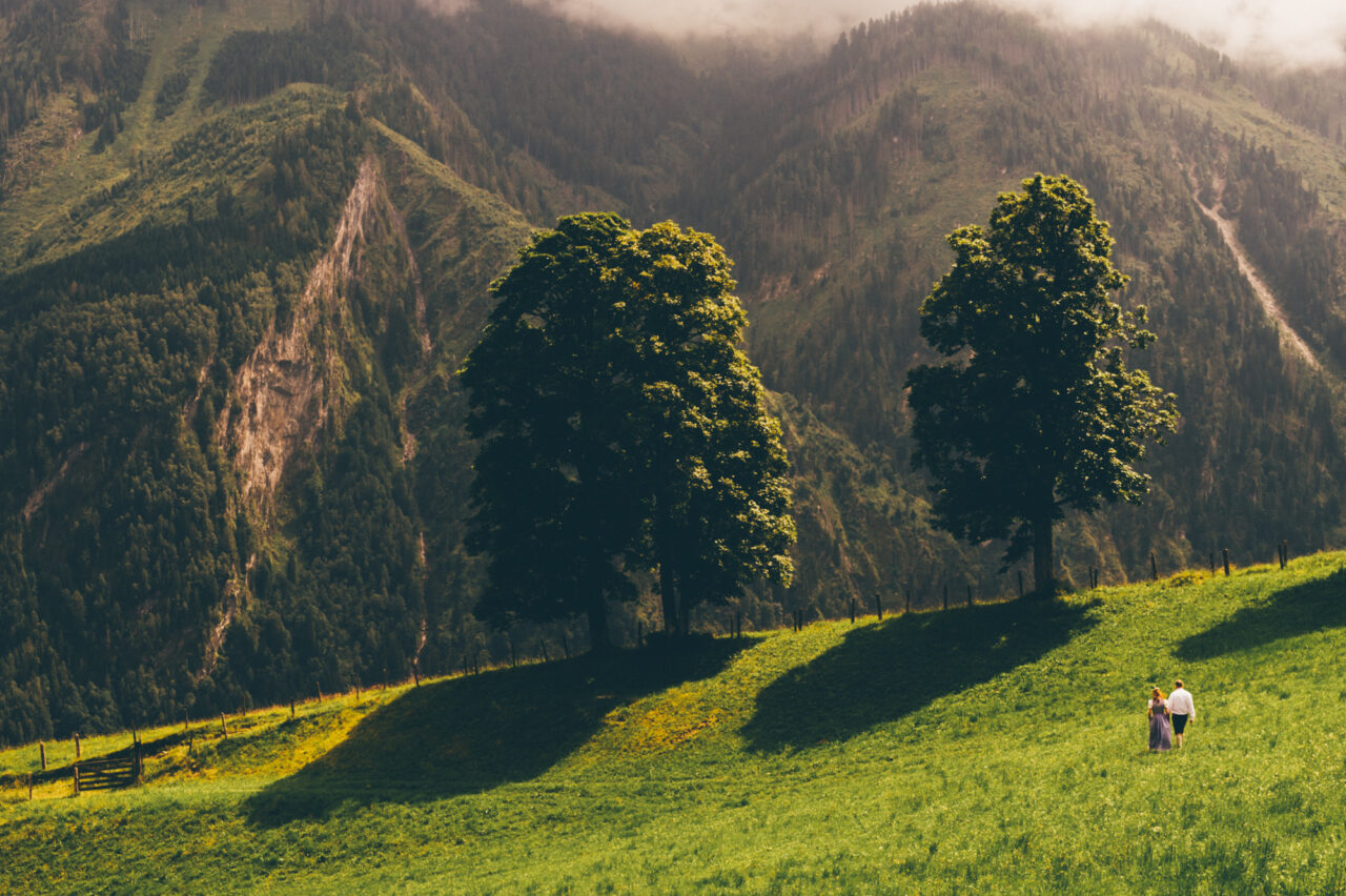 A bride and groom walk towards some mountains.