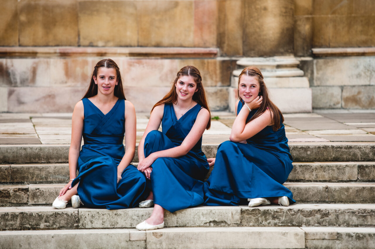 Three flower girls on the steps of The Wren Library in Trinity College in Cambridge.