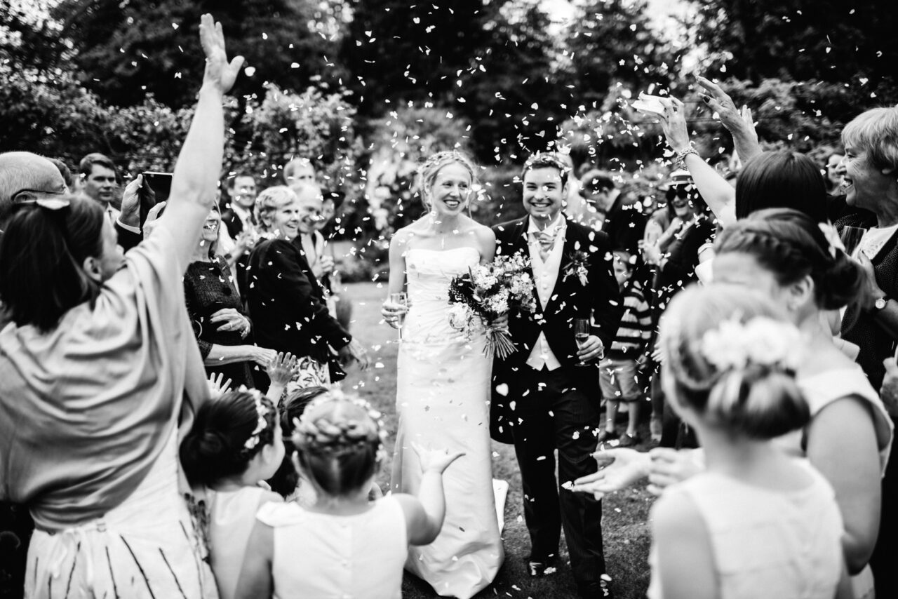 Cambridge wedding photographer - a bride and groom are showered with confetti