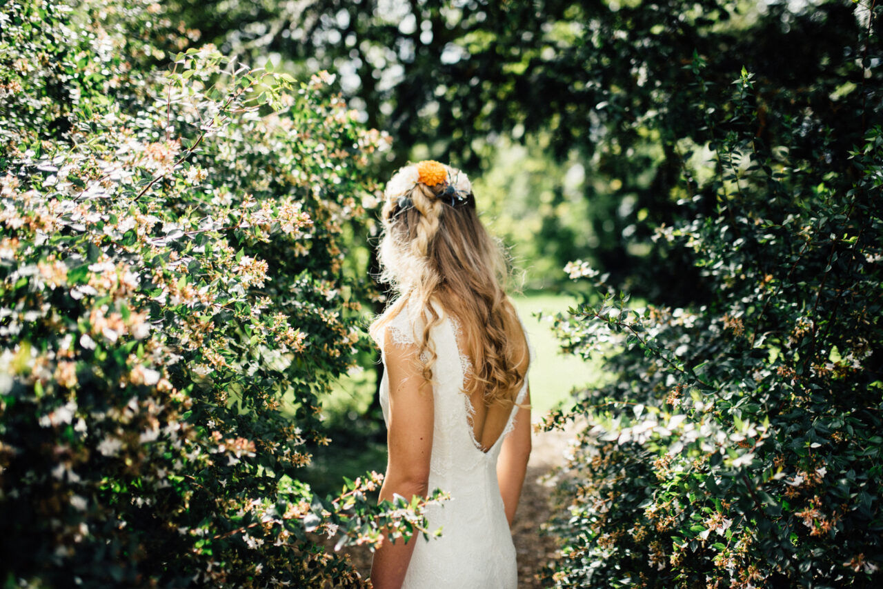 A bride with her back turned slightly to the camera in the garden of Island Hall.