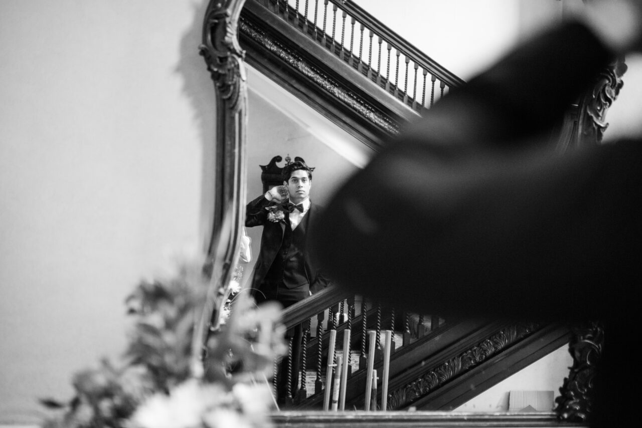 A groom looks at his reflection in a large mirror inside Island Hall in Cambridgeshire.