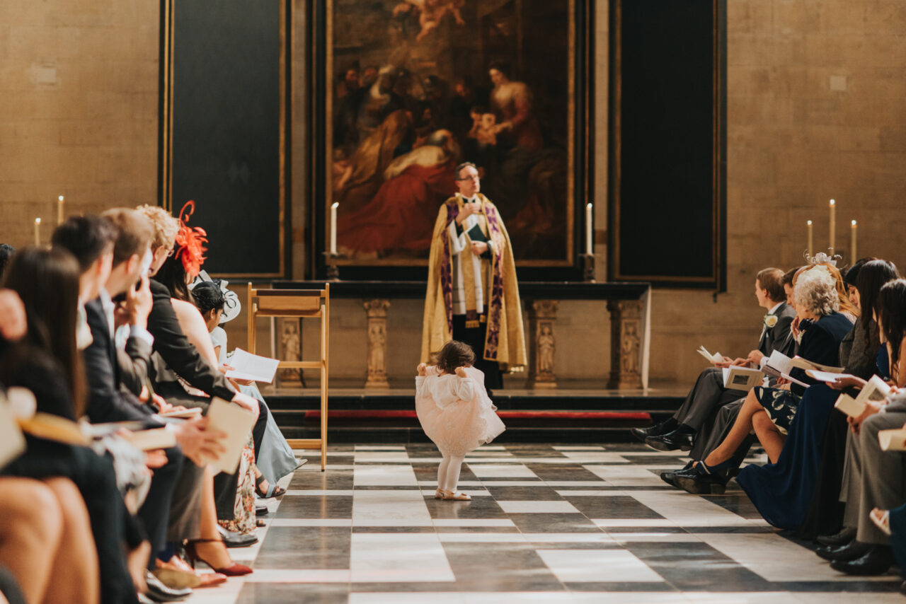 A young girl plays in the aisle at a wedding in King's College Chapel.