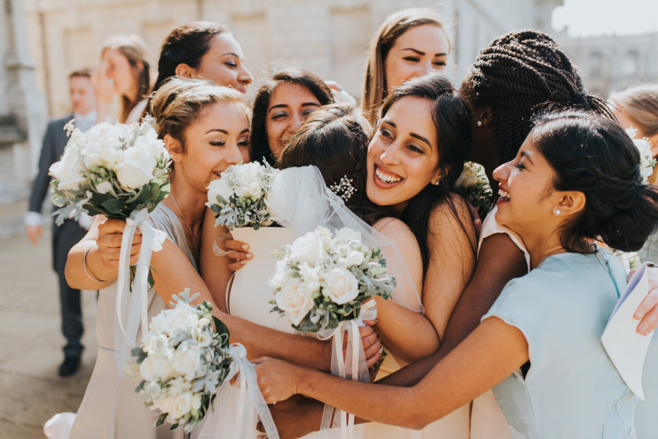 King's College wedding photography of bridesmaids hugging the bride.