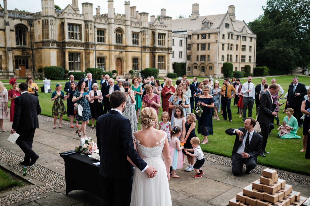 A crowd is gathered outside in the grounds of King's College in Cambridge to hear wedding speeches.