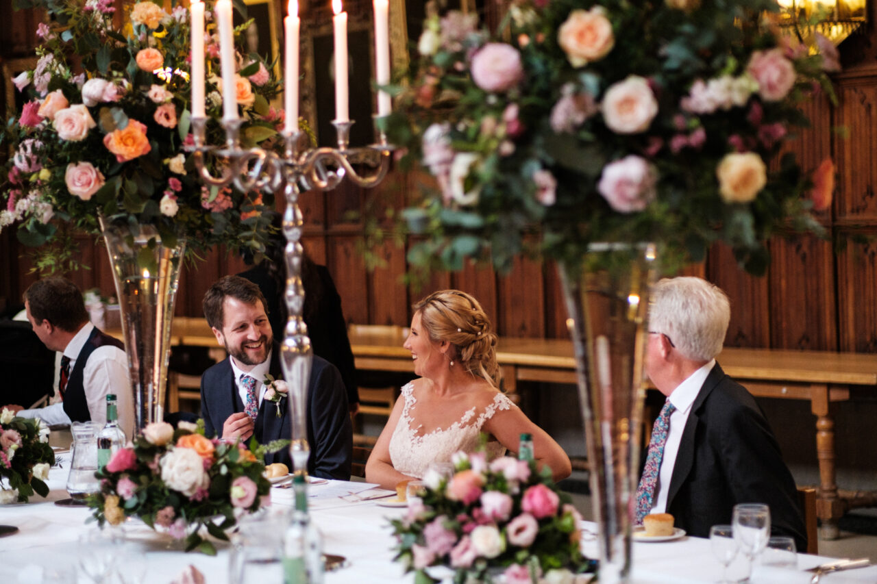 A bride and groom laugh during their wedding breakfast at King's College Hall