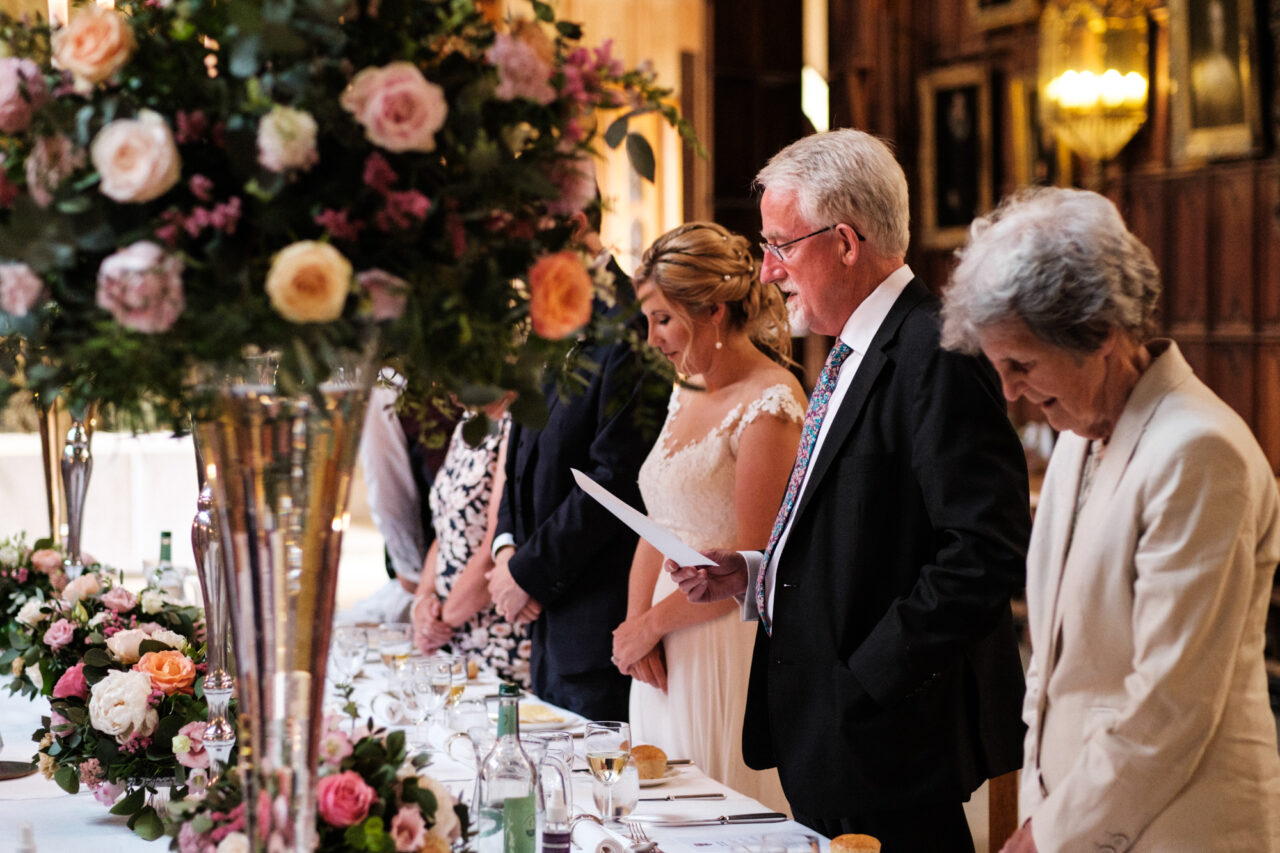 The father of the groom says grace before dinner at King's College in Cambridge.