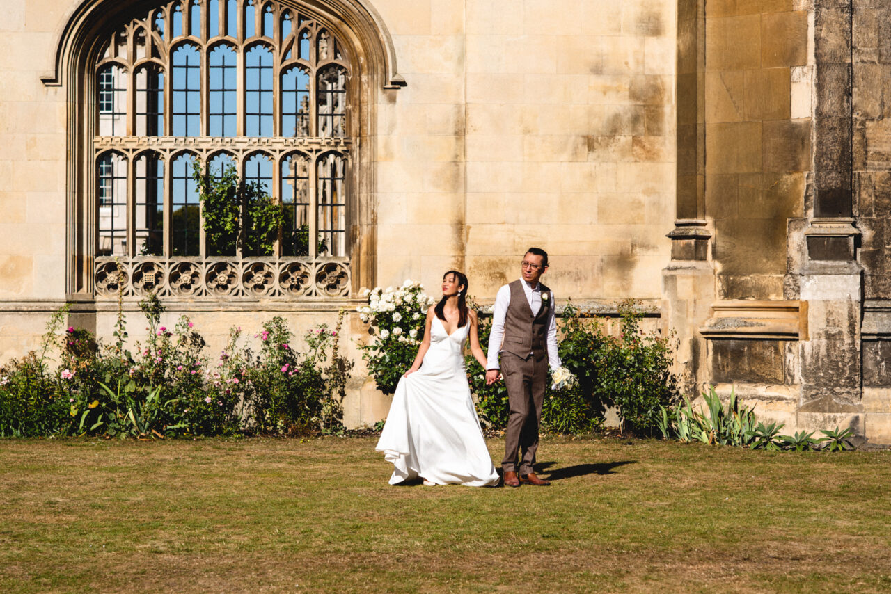 A bride and groom walk in the ground's of King's College on King's Parade.