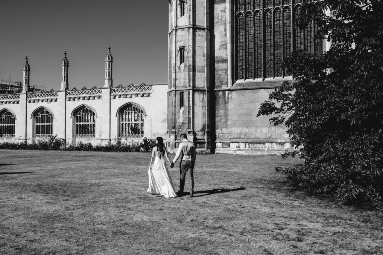A bride and groom walk in the ground's of King's College near King's Parade.
