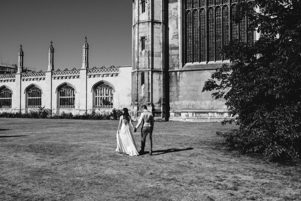 A bride and groom walk in the ground's of King's College near King's Parade.