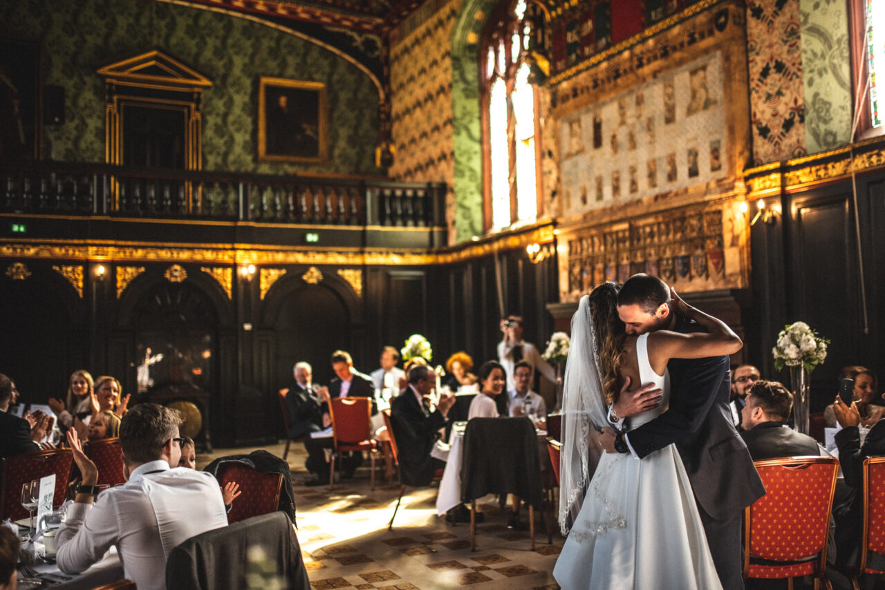 A bride and groom dance their first dance in the beautiful Old Hall at Queens' College in Cambridge.