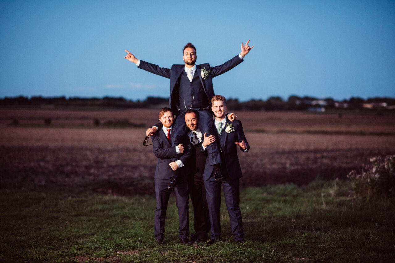 Groomsmen hold the groom on their shoulders at a wedding at Burleigh Hill Farm.