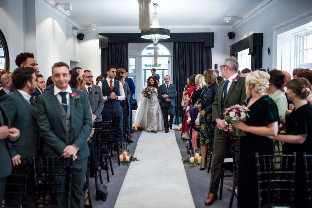 Bride and her father walk down the aisle inside Swynford Manor for her wedding.