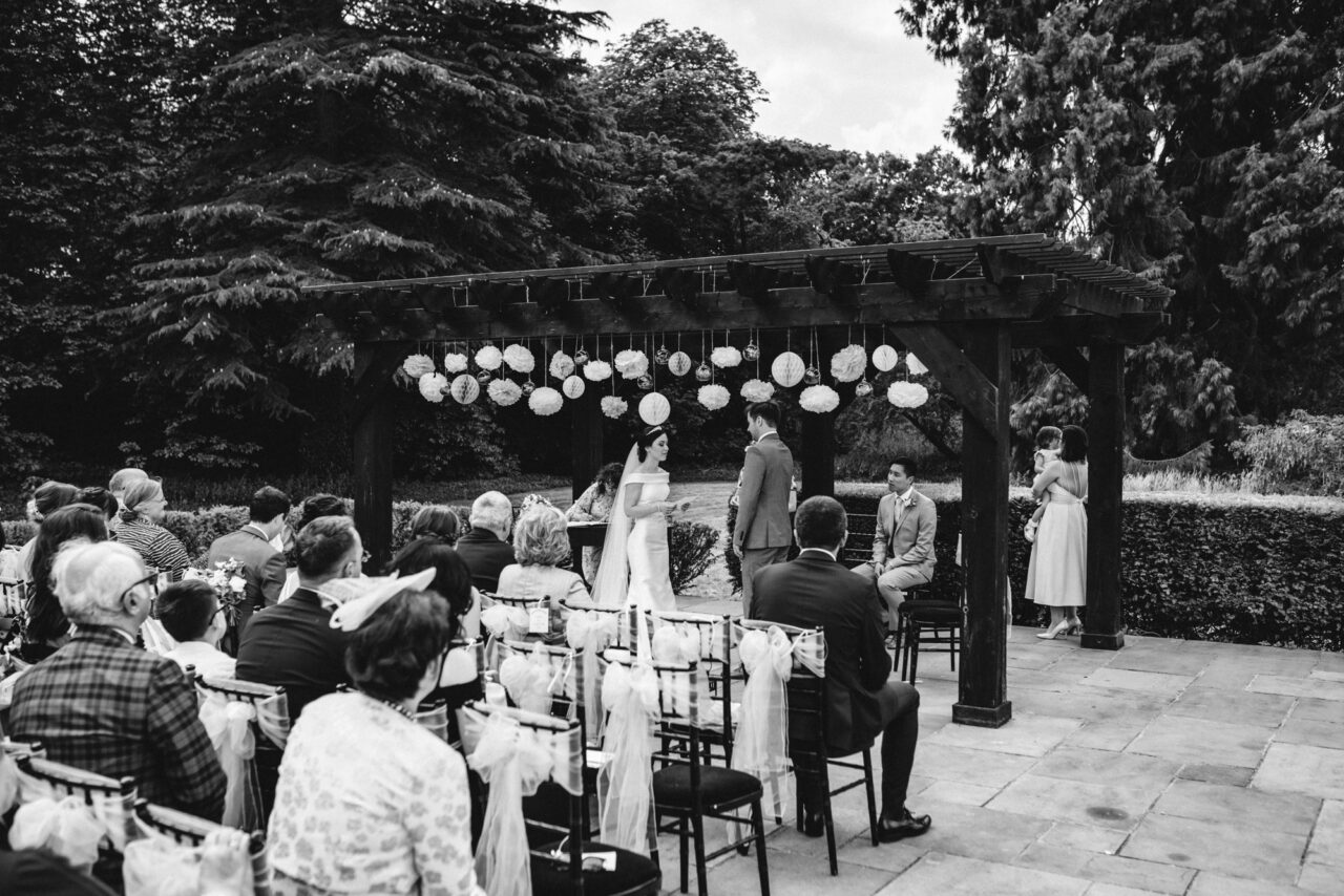 A bride and groom exchange vows at an outdoor wedding at Swynford Manor.