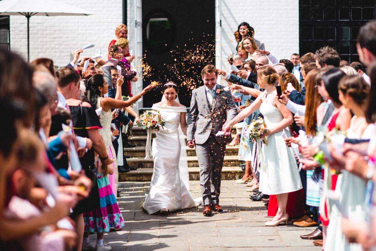 Bride and groom are showered with confetti at their Swynford Manor wedding.