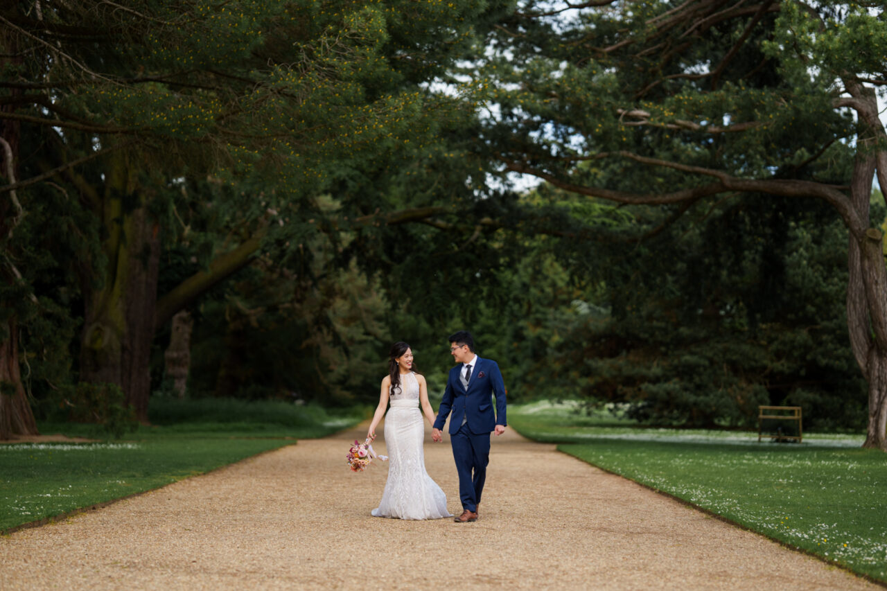 A young couple walk holding hands through Cambridge University Botanic Garden.