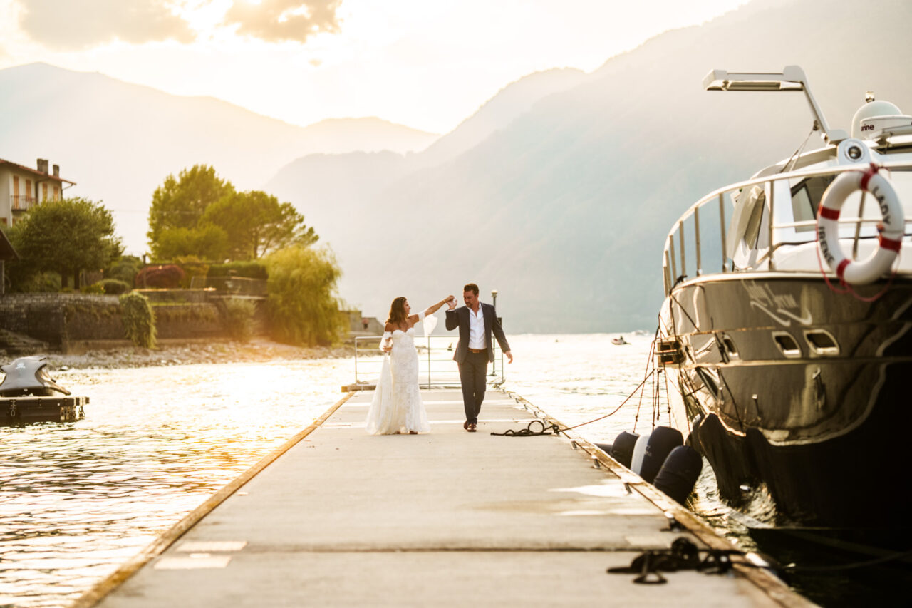 Bride and groom walking on a jetty in Lake Como at sunset.