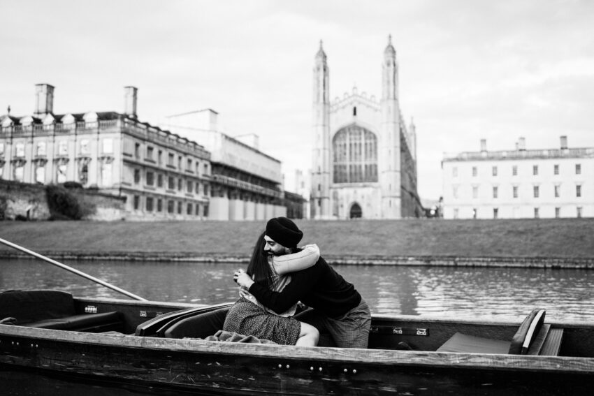 A couple embrace during a surprise proposal on a punt in Cambridge.