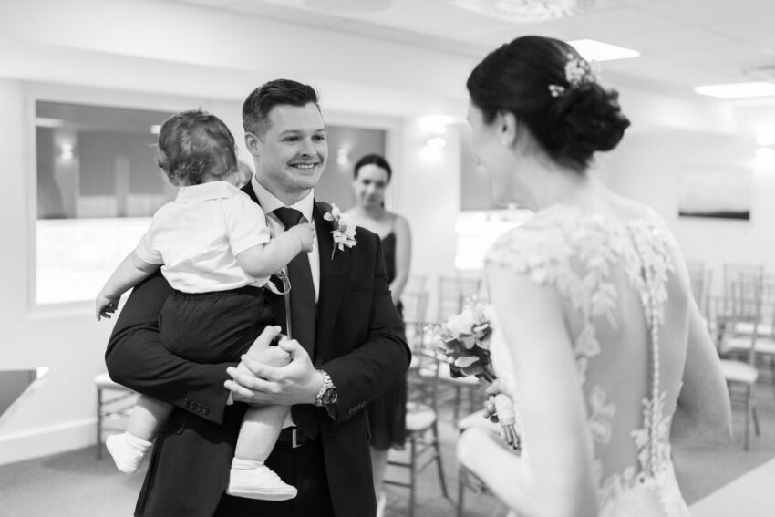 Groom smiles at bride in The Brooke Room at Cambridgeshire Register Office.