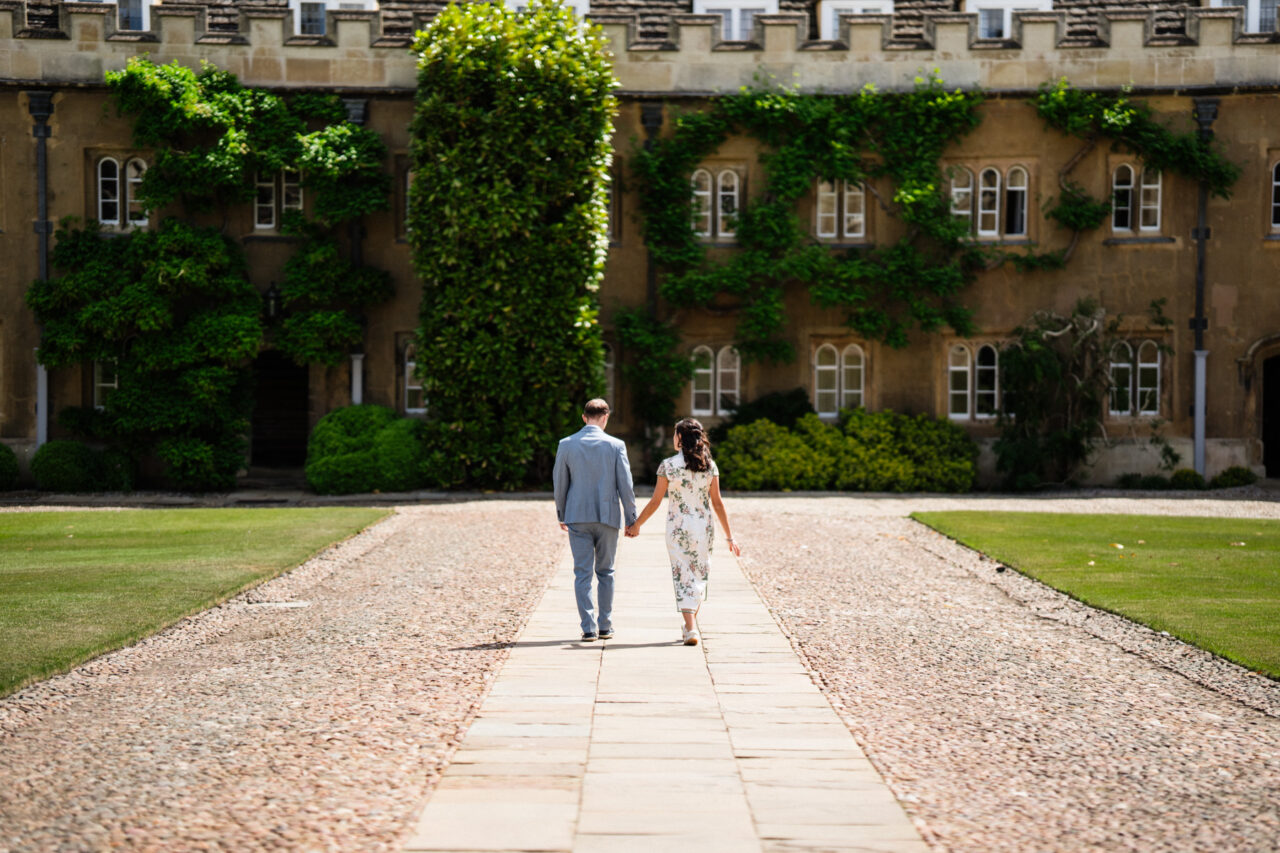 A couple walk hand in hand in Trinity College Cambridge.