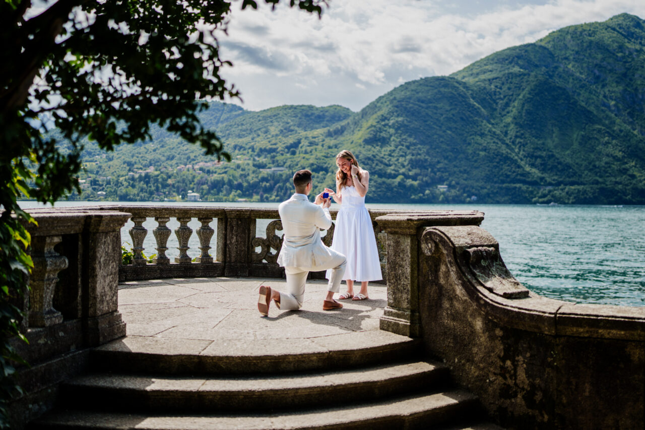 Romantic proposal as a man kneels with a ring and proposes to his girlfriend in Tremezzo, Lake Como in Italy