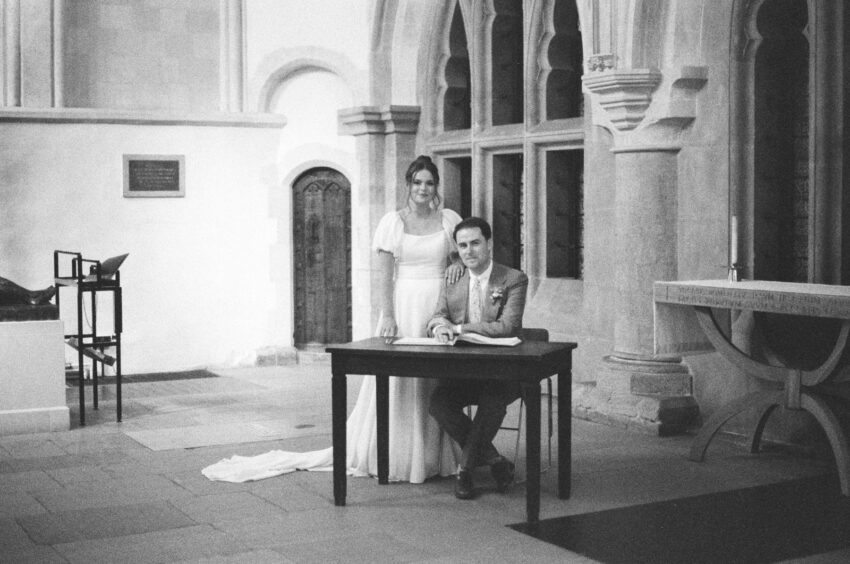 Black and white film photo of the bride and having signed the register at Jesus College in Cambridge.